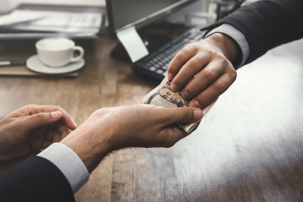 A hand passing money across a table in a loan transaction.