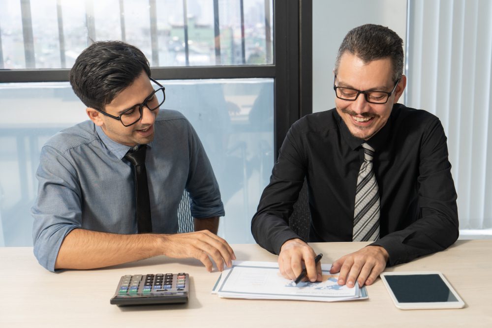 Two professionals signing documents for commercial loans.